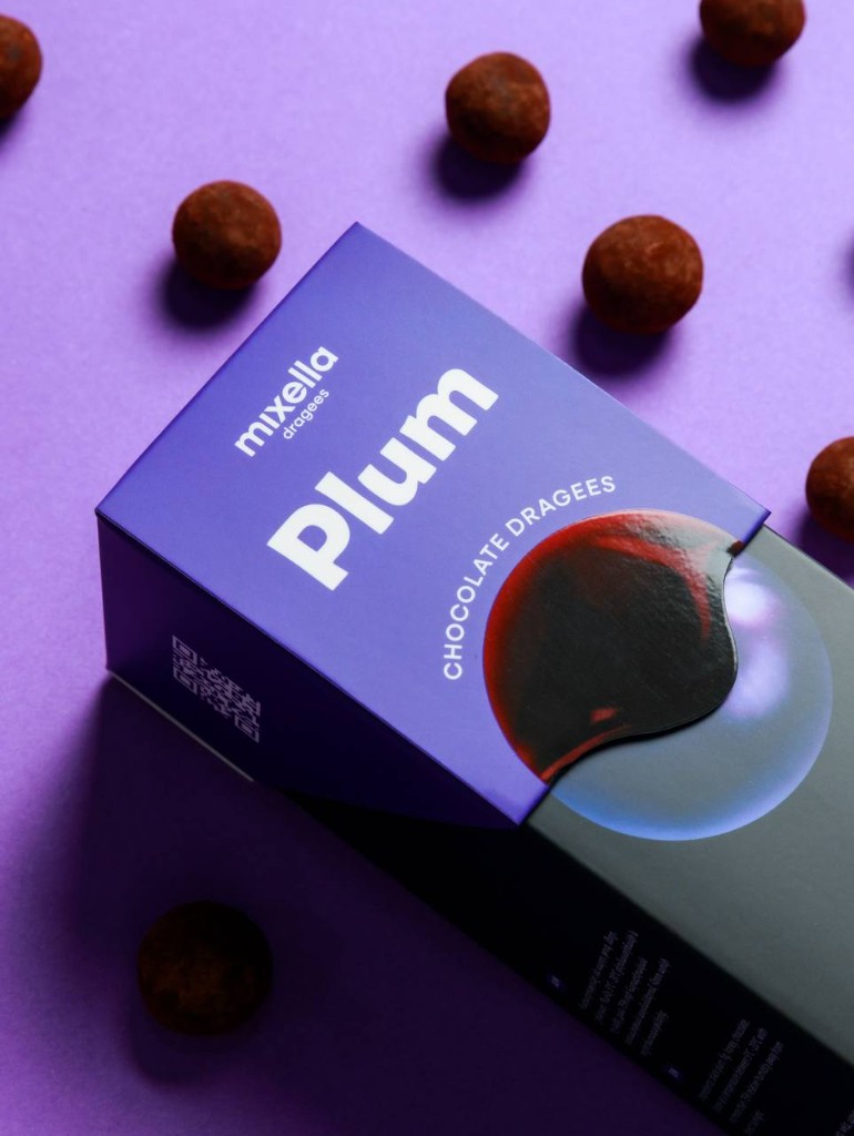 Mixella plum chocolate dragees box on purple with scattered pieces